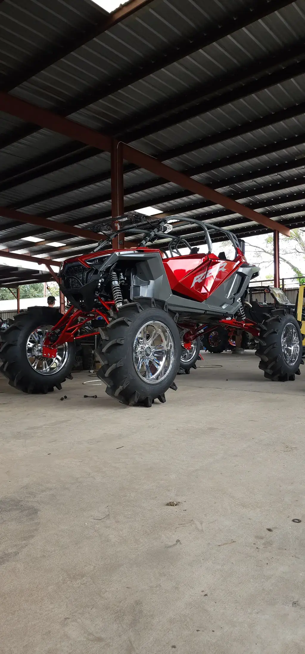Custom-built Polaris RZR off-road buggy on oversized mud tires under the covered shop structure at D H Tire